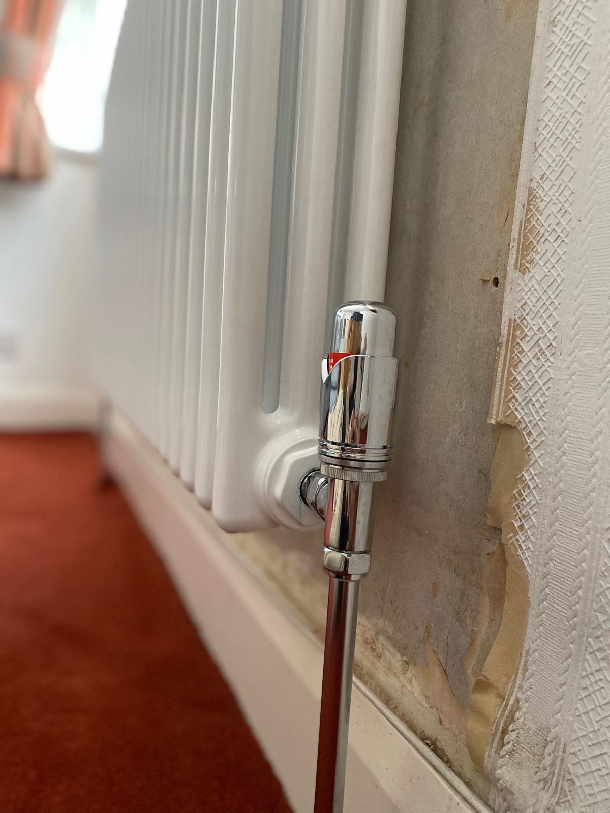 Chrome thermostatic valve and pipe connection on a white column radiator