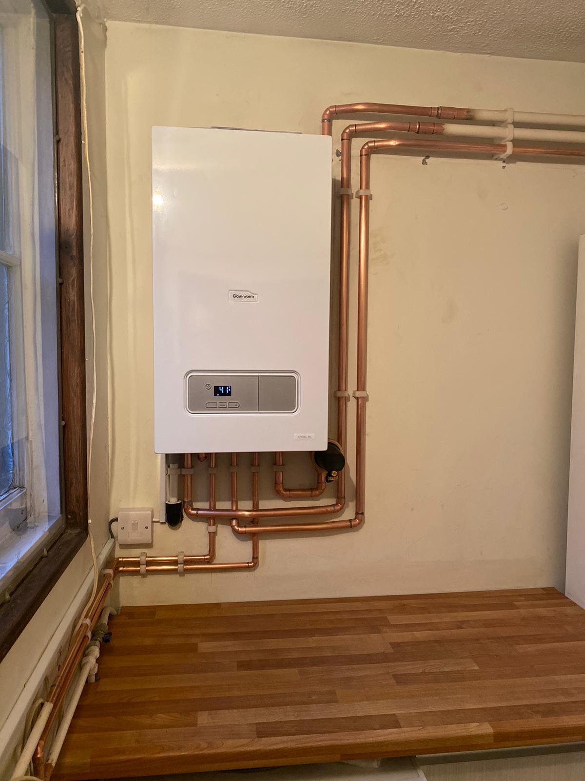 White boiler above a timber worktop with copper pipework