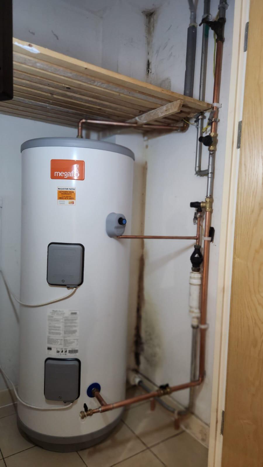 Megaflo cylinder with associated copper pipework beneath an airing cupboard shelf