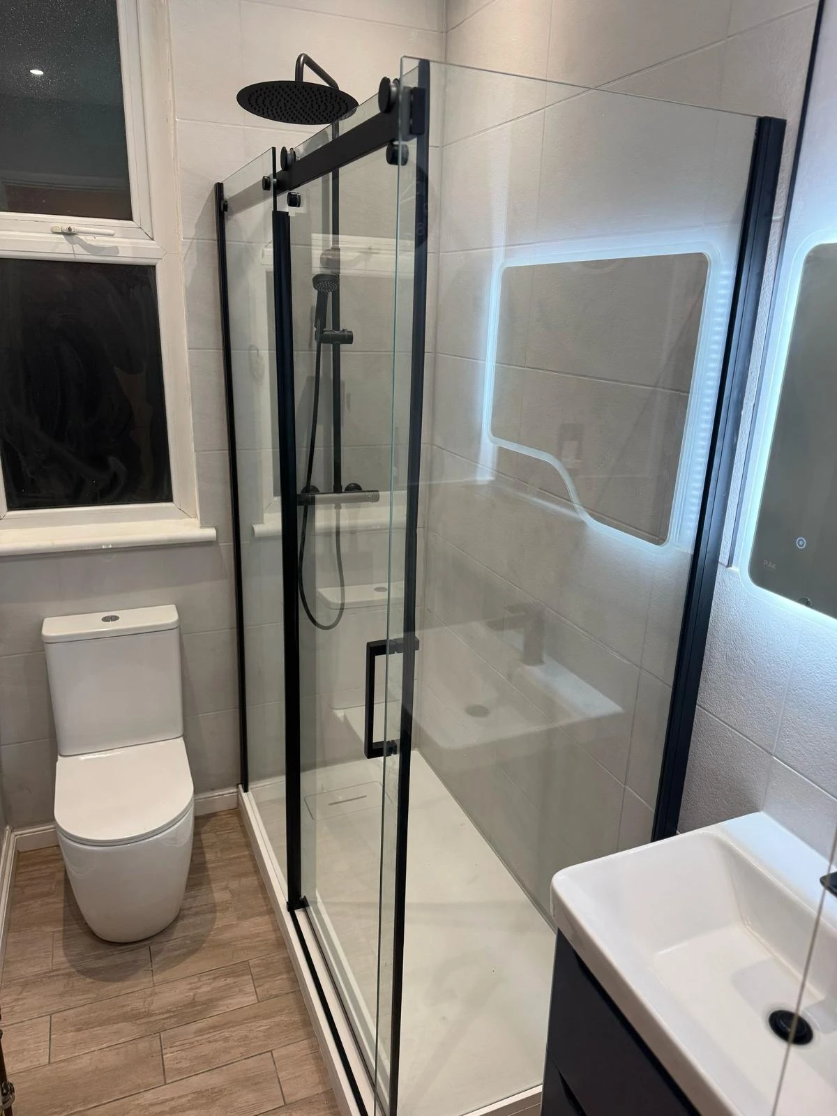 Shower room with black framed enclosure, black shower fittings and illuminated mirror