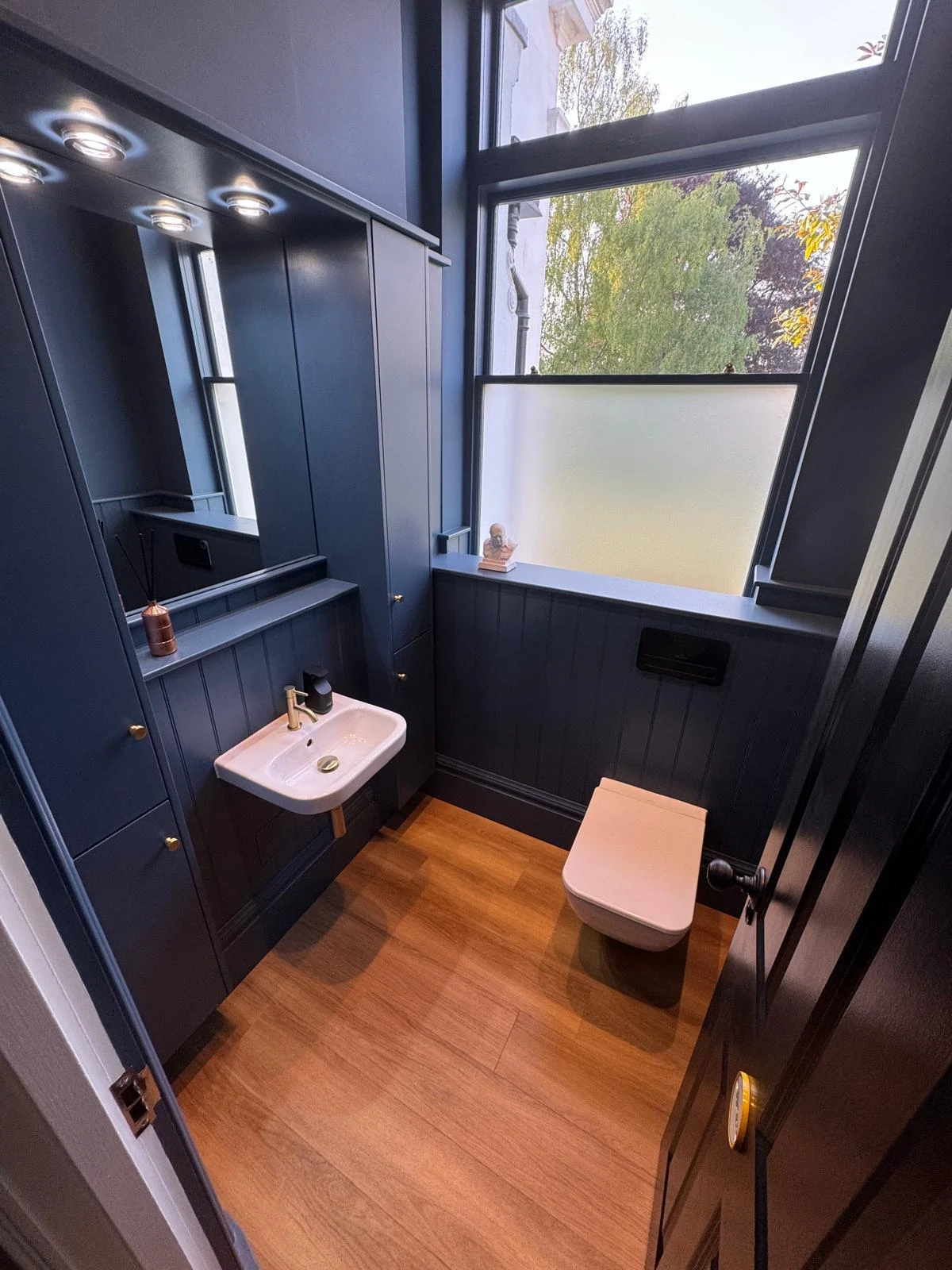 Blue-panelled cloakroom by Star Boilers with brass fittings and wooden flooring