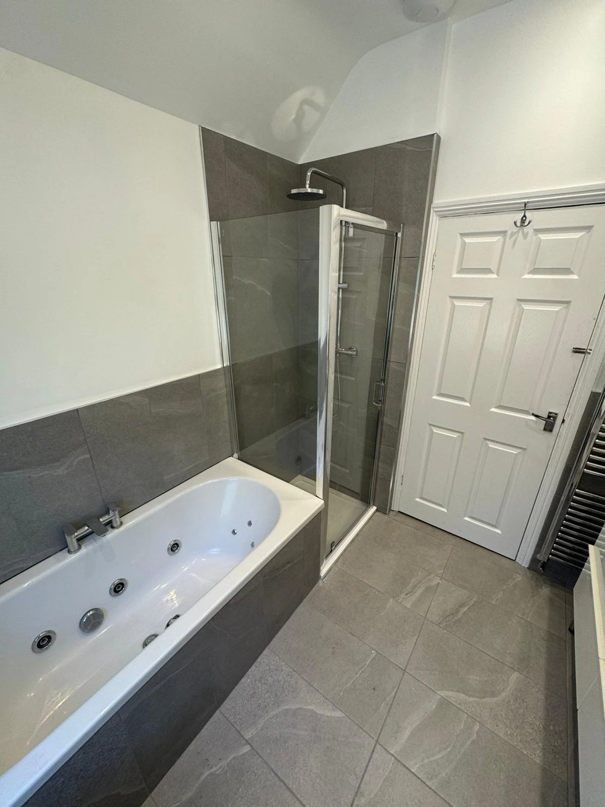 Grey tiled bathroom with whirlpool bath and separate shower