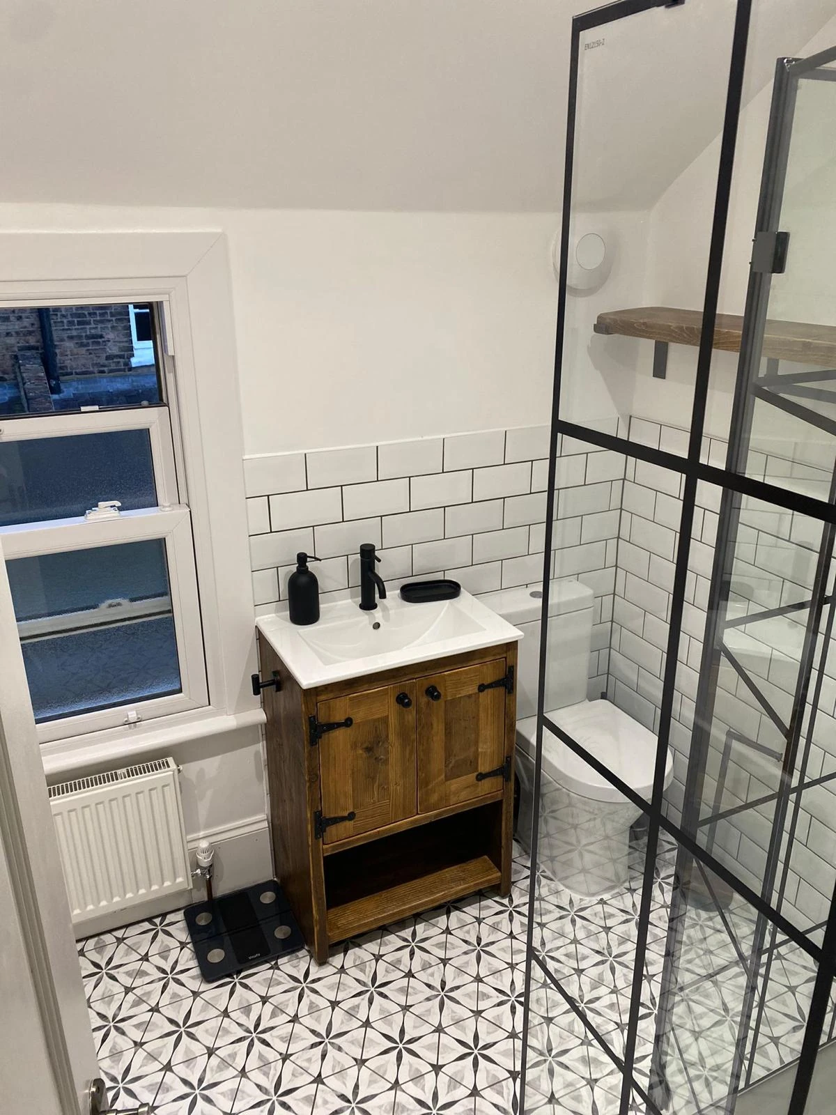 Bathroom with timber vanity, black framed shower screen and patterned tiles
