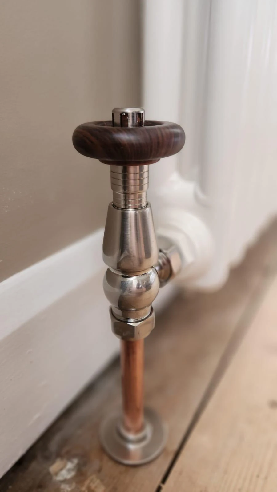 Traditional radiator valve with wooden handle and copper pipework