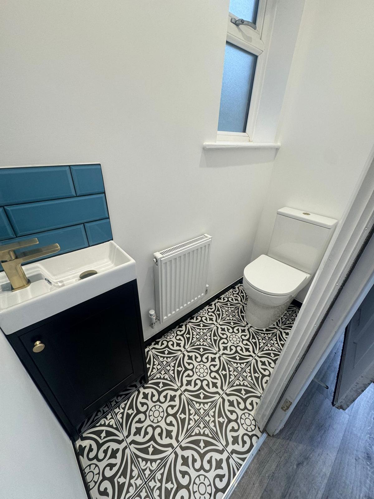 Compact cloakroom with teal basin tiles, dark vanity and patterned floor